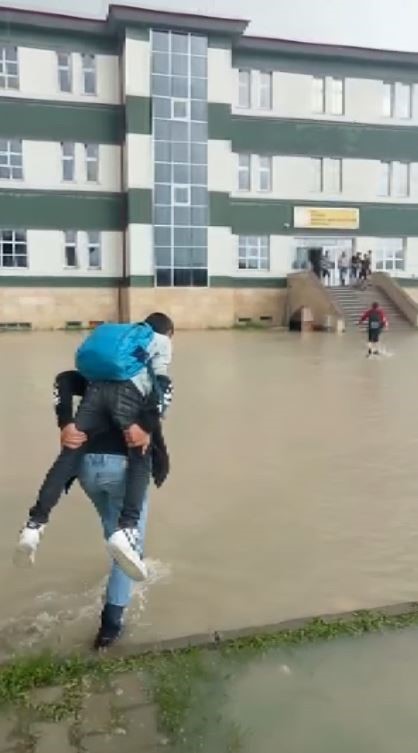 Okul bahçesi sular altında kaldı, öğrenciler birbirini sırtladı