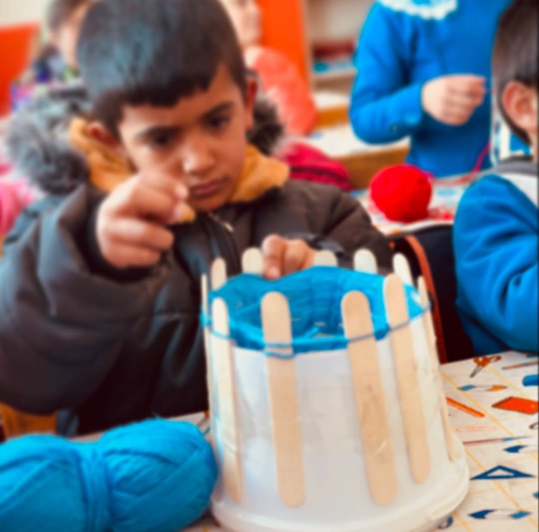 Minik öğrenciler yoğurt kovalarından atkı örüyor